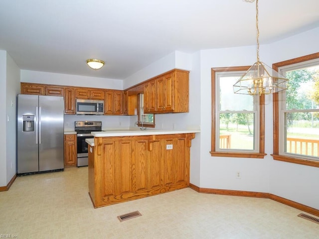 kitchen with an inviting chandelier, hanging light fixtures, kitchen peninsula, and appliances with stainless steel finishes