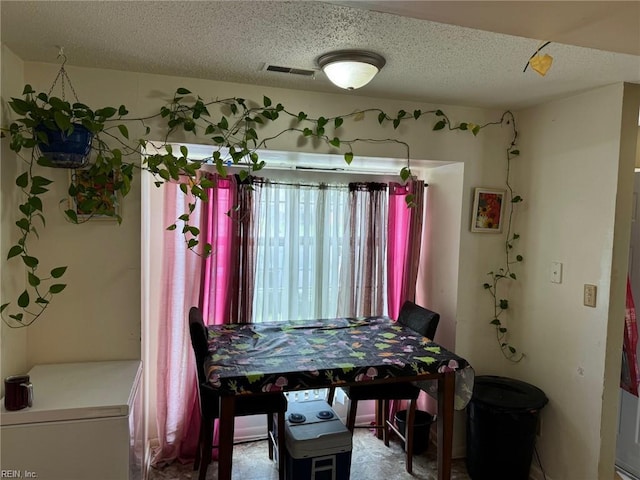 tiled dining space with a textured ceiling