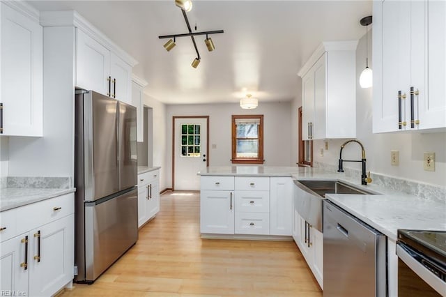 kitchen with stainless steel appliances, white cabinets, kitchen peninsula, hanging light fixtures, and light hardwood / wood-style floors