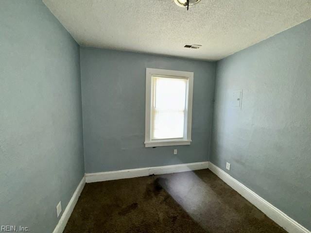 carpeted spare room featuring baseboards, a textured ceiling, and visible vents