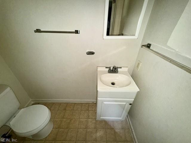 half bathroom with toilet, baseboards, and vanity