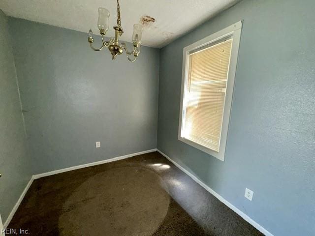 unfurnished dining area featuring baseboards, dark carpet, and a notable chandelier