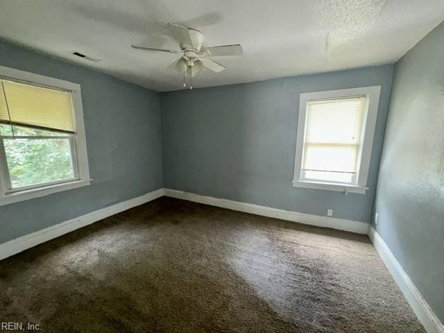 empty room featuring baseboards, ceiling fan, dark carpet, and visible vents