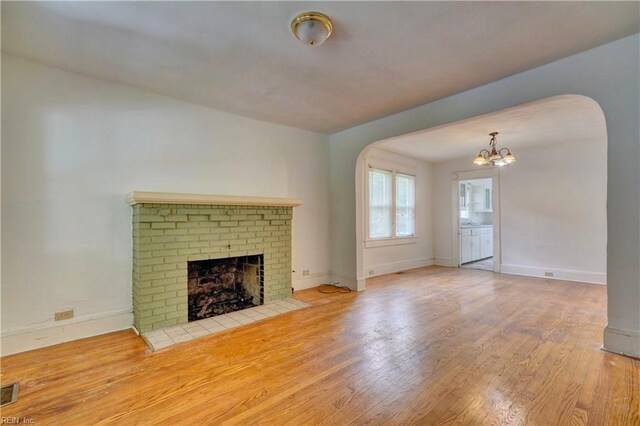 unfurnished living room featuring a brick fireplace and light wood-type flooring