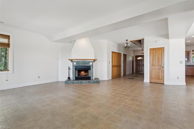 188 Tranquility Rd, Reedville, VA 22539 - unfurnished living room featuring a tiled fireplace, baseboards, and a notable chandelier