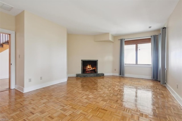 unfurnished living room with a tiled fireplace and light parquet flooring