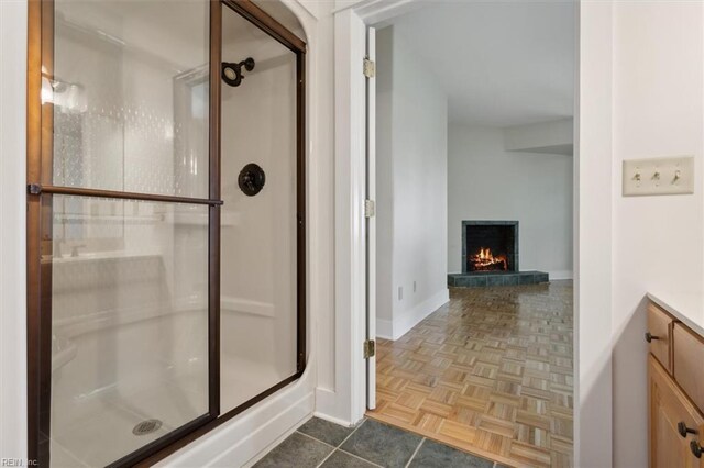 188 Tranquility Rd, Reedville, VA 22539 - bathroom featuring baseboards, a warm lit fireplace, and a stall shower