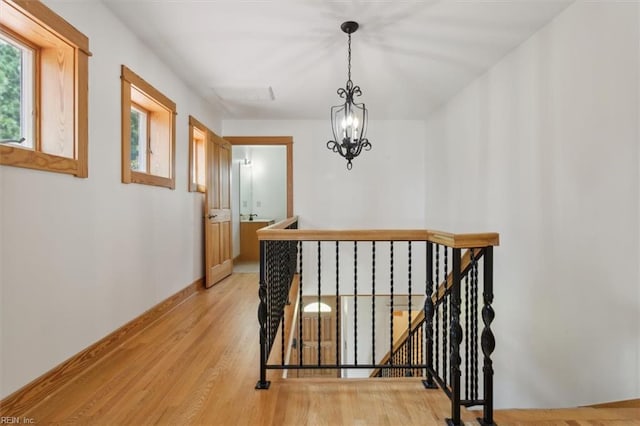 hallway with light hardwood / wood-style flooring and a chandelier