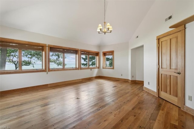 unfurnished bedroom with high vaulted ceiling, a chandelier, and light wood-type flooring