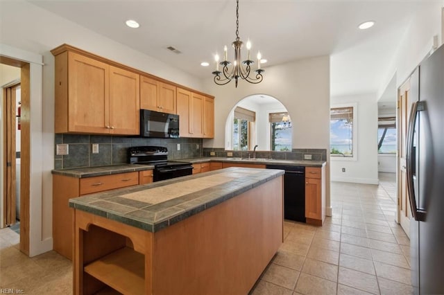 kitchen with a center island, black appliances, light tile patterned floors, and backsplash