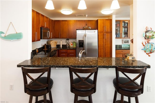 kitchen with a breakfast bar, a peninsula, pendant lighting, and stainless steel appliances