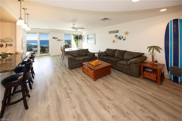 living room featuring ceiling fan, a water view, and light hardwood / wood-style flooring