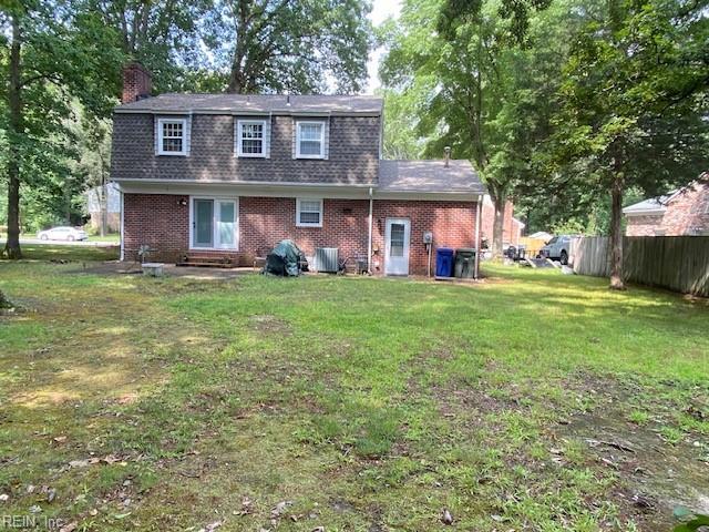 rear view of house featuring central AC unit and a yard