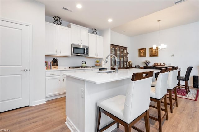 kitchen with sink, white cabinetry, appliances with stainless steel finishes, an island with sink, and pendant lighting