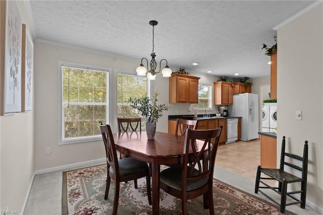 dining space featuring an inviting chandelier, ornamental molding, washer and dryer, and a textured ceiling