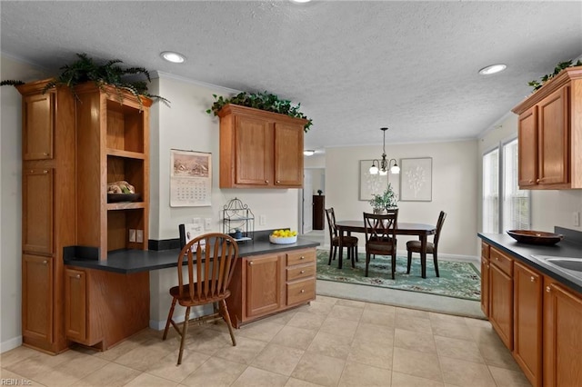 kitchen featuring hanging light fixtures, built in desk, kitchen peninsula, and a textured ceiling