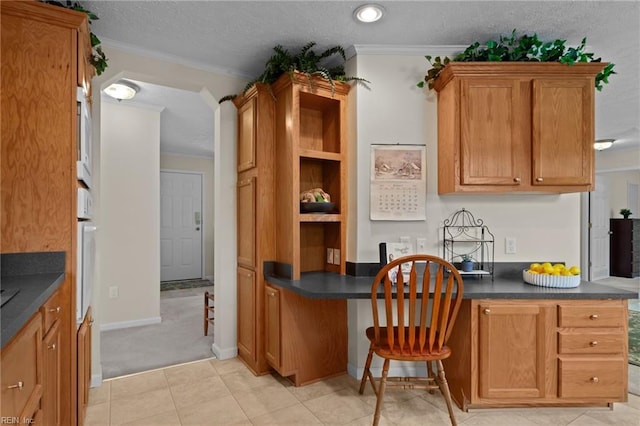 kitchen with crown molding, built in desk, a textured ceiling, and light tile patterned floors