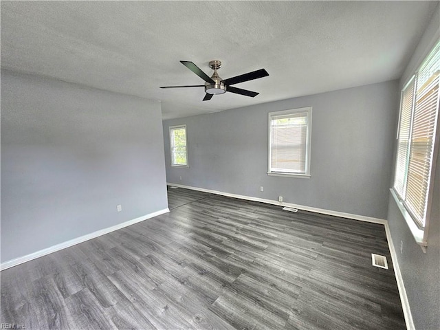 unfurnished room with a textured ceiling, plenty of natural light, ceiling fan, and dark wood-type flooring