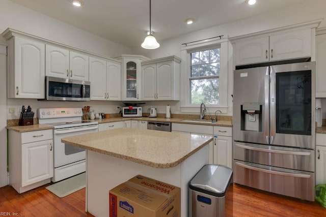 kitchen featuring white cabinets, a center island, stainless steel appliances, hardwood / wood-style floors, and sink