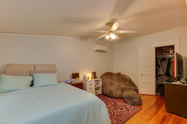 bedroom featuring ceiling fan, a wall mounted AC, light hardwood / wood-style flooring, and a closet