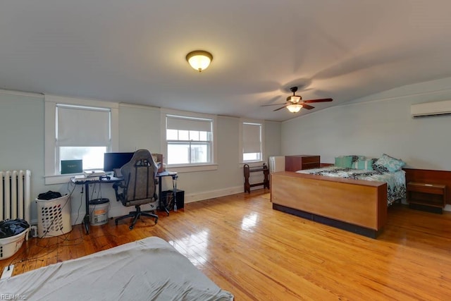 bedroom featuring vaulted ceiling, a wall mounted AC, light wood-type flooring, radiator heating unit, and ceiling fan