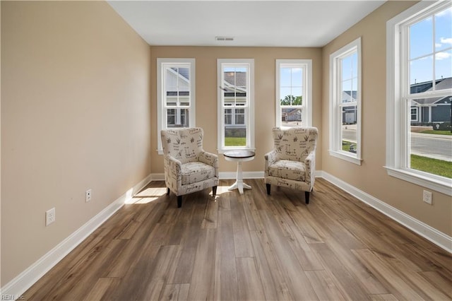 sitting room with wood finished floors, visible vents, and baseboards