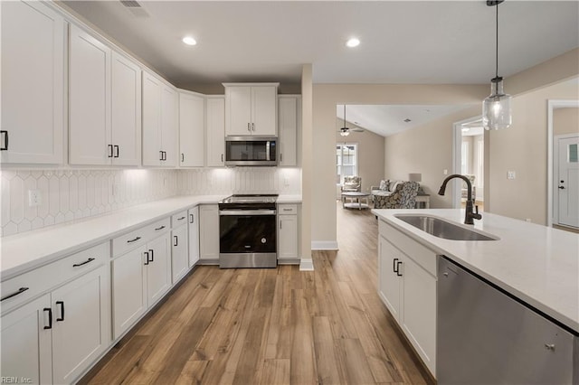 kitchen featuring pendant lighting, appliances with stainless steel finishes, white cabinetry, a sink, and light wood-type flooring