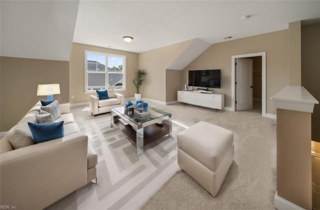 living area featuring baseboards, lofted ceiling, and light colored carpet