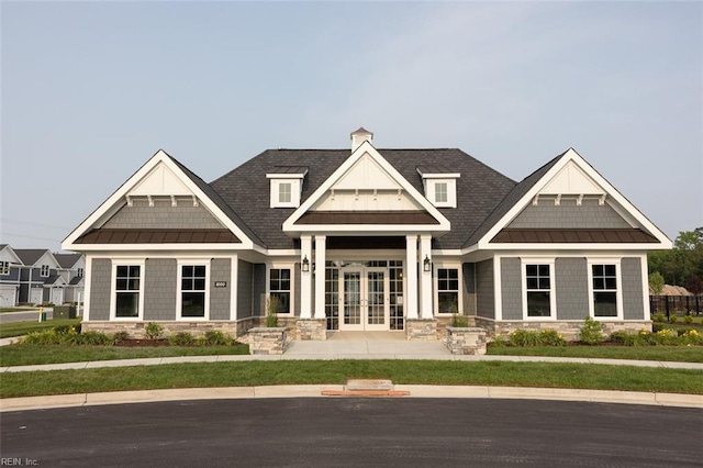 view of front of home with stone siding, french doors, and a standing seam roof