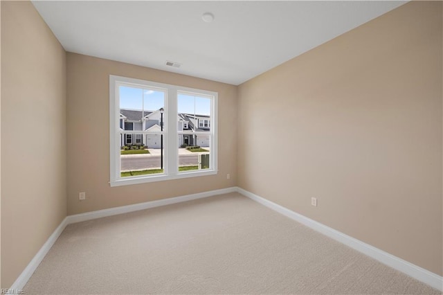 empty room with light carpet, visible vents, and baseboards