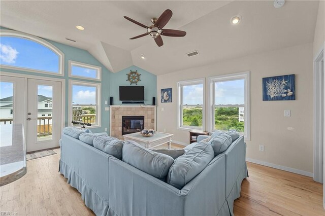 living room featuring light wood-type flooring, a fireplace, french doors, ceiling fan, and vaulted ceiling