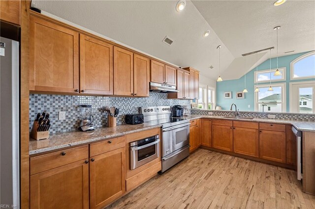 kitchen with stainless steel appliances, light wood-type flooring, vaulted ceiling, sink, and decorative light fixtures