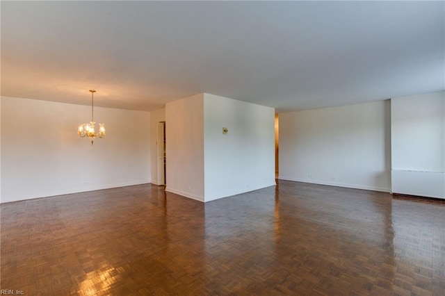 empty room with an inviting chandelier and dark parquet flooring