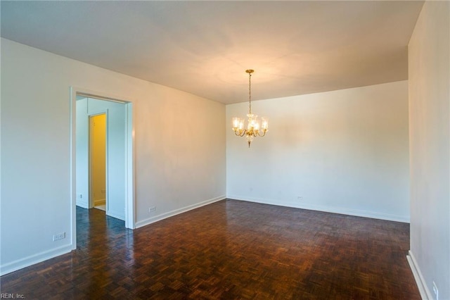 empty room featuring dark parquet floors and an inviting chandelier