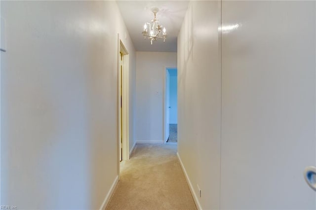 hallway featuring a chandelier and light carpet