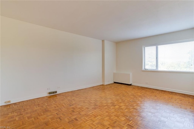 empty room with radiator and light parquet floors