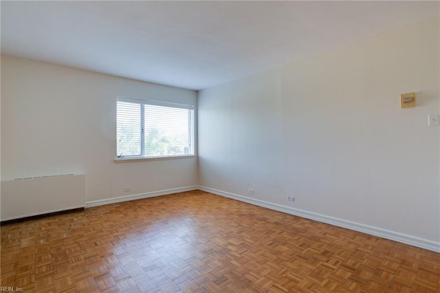 unfurnished room with radiator heating unit and parquet flooring