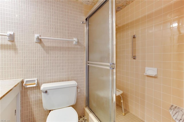 bathroom with toilet, vanity, tile walls, tile patterned floors, and walk in shower