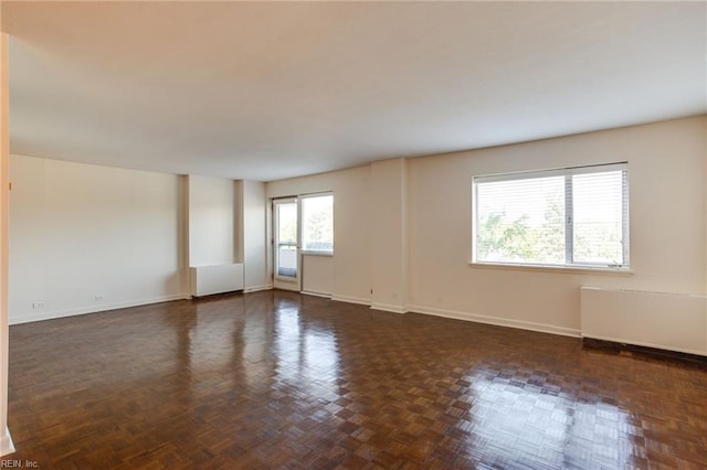 spare room with a wealth of natural light and dark parquet floors