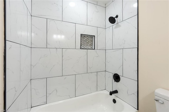 bathroom featuring toilet and tiled shower / bath