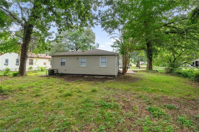 rear view of house with central AC unit and a yard