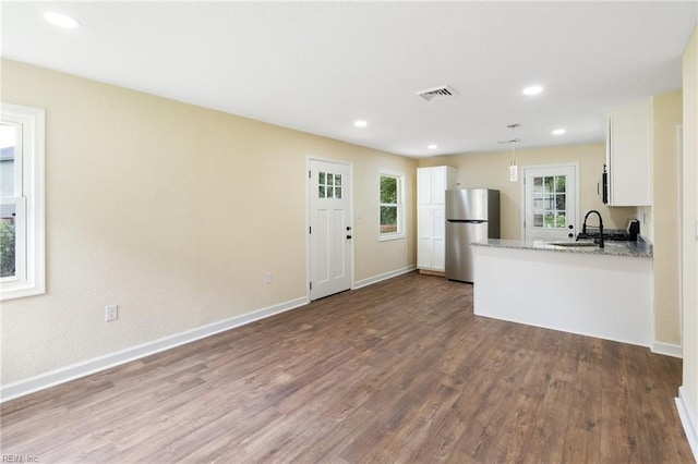 kitchen featuring light stone counters, white cabinets, light hardwood / wood-style floors, stainless steel appliances, and sink