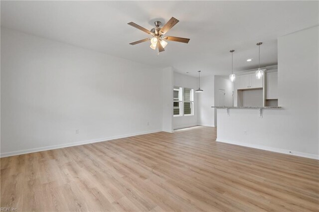 unfurnished living room featuring ceiling fan and light wood-type flooring