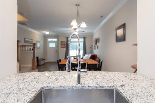 kitchen featuring ornamental molding, pendant lighting, light stone countertops, and sink