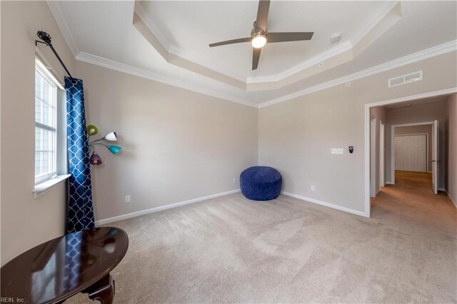 interior space featuring light colored carpet, ceiling fan, a raised ceiling, and crown molding