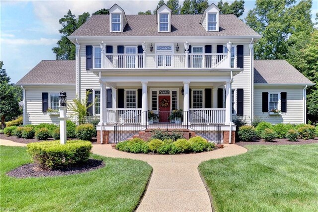 view of front of house featuring a balcony, a front yard, and covered porch