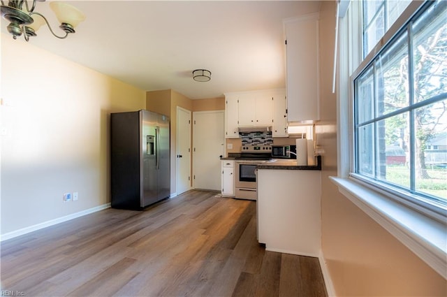 kitchen featuring a notable chandelier, light wood-type flooring, decorative backsplash, stainless steel appliances, and white cabinets