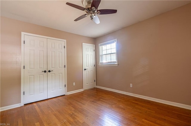 unfurnished bedroom with ceiling fan, wood-type flooring, and multiple closets