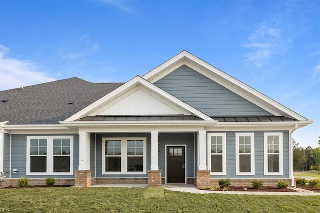 craftsman-style home with metal roof, brick siding, a standing seam roof, and a front lawn