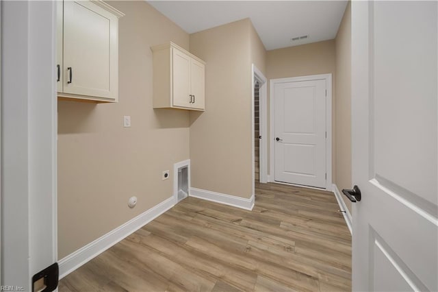 clothes washing area featuring cabinet space, baseboards, gas dryer hookup, light wood-type flooring, and electric dryer hookup